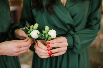 A bridesmaid in green dresses holding buttonholes closeup