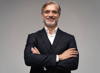 Handsome smiling middle-aged man in suit posing against grey background