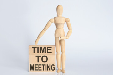 Wooden man shows with a hand text TIME TO MEETING concept on the wooden block