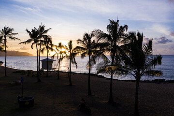 Little lifeguard cottage between palm trees on a Caribbean beach on Hawaii with a colorful view of the calm sea at sundown