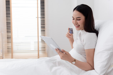 Asian beauty Currently using a credit card to make purchases using the tablet via the internet With a happy smiling face, being a new normal online business In the shopping experience from home