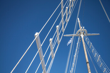 White sail mast with Greek flag and clear blue sky in background