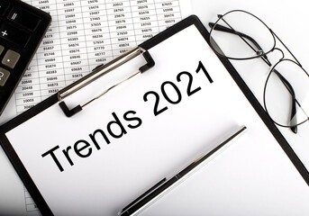 TRENDS 2021 text with calculator, glasses and pen on chart background