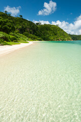 Perfect tropical beach, crystalline emerald green sea, smooth sands, green mountains, blue sky. Iriomote Island.