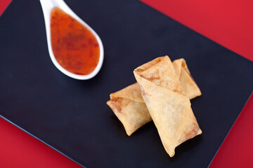 A plate of fried spring rolls at the beginning of spring on a red background
