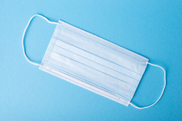 One new disposable medical mask on a blue background. Concept of medicine