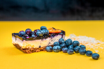 gourmet cheesecake with red berries blueberries strawberry and orange on a yellow background