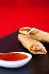 A plate of fried spring rolls at the beginning of spring on a red background