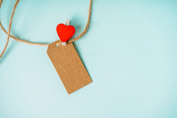 Craft tag with a place for text and a clothespin in the form of a heart on a blue background. Greeting card concept for loved ones