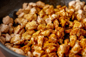 finely chopped chicken fillet fried in curry spices for salad preparation, ingredients on a plate on a wooden background