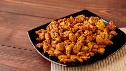 finely chopped chicken fillet fried in curry spices for salad preparation, ingredients on a plate on a wooden background