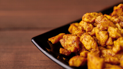 finely chopped chicken fillet fried in curry spices for salad preparation, ingredients on a plate on a wooden background