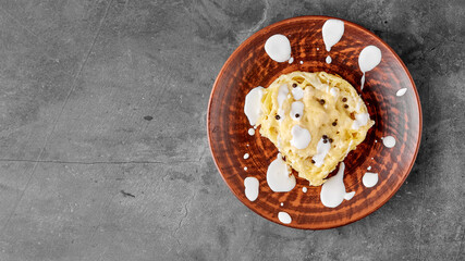 A plate of spaghetti stuffed with chicken fillet and cheese on the table next to a basket of bread. Decoration with drops of cream sauce. Gray texture background top view. Menu Of Dishes. Copy space.