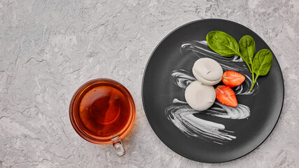 Homemade marshmallow on a gray plate with strawberries and a green leaf. Marshmallow with a cup of...