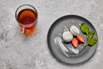 Homemade marshmallow on a gray plate with strawberries and a green leaf. Marshmallow with a cup of...