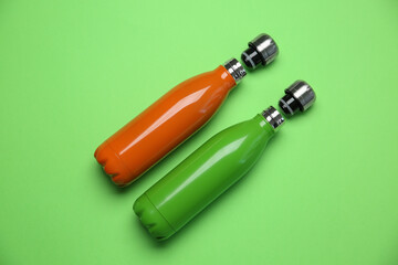 Different thermo bottles on green background, flat lay