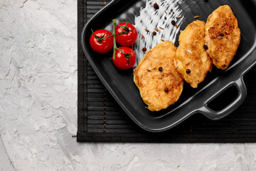Traditional chicken schnitzel and cherry tomatoes on a gray concrete background. Chicken cutlets...