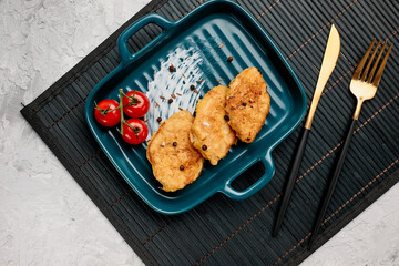 Traditional chicken schnitzel and cherry tomatoes on a gray concrete background. Chicken cutlets...