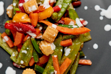 Baked vegetables on a brown plate on a gray textured background top view. Drops of sour cream as a dish decoration. Food menu. Place to copy text