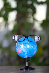 A globe with glasses in front of a virtual green background