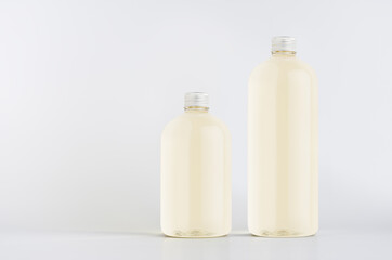 Set of two plastic tall and low bottles with pale fresh drink or cosmetic essential oil, silver cap mockup on white background, template, copy space.