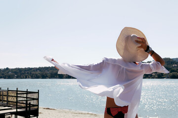 Rear view of carefree woman by the water during summer day.