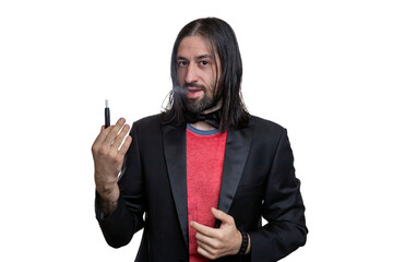 A man with long hair and a beard with an electronic cigarette with sticks in his hands on a white background. He is wearing a black jacket and a red T-shirt and a bow tie around his neck.