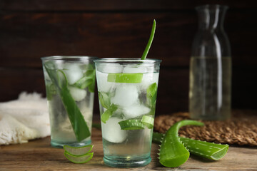 Fresh aloe drink with ice cubes on wooden table