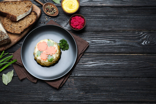 Delicious homemade chicken aspic served on black wooden table, flat lay. Space for text