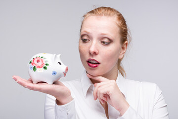 Fototapeta na wymiar happy red-haired woman with a piggy bank