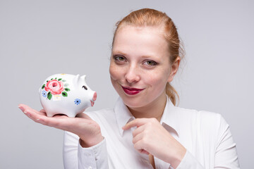 Fototapeta na wymiar happy red-haired woman with a porcelain bank 