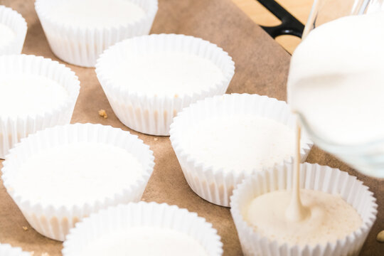 Closeup Of Cheesecake Batter Pouring Into Cupcake Liners On A Sheet Pan