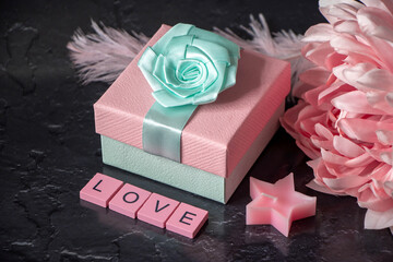 Beautiful pink composition and a black background. Dahlia flower, present box and word love made of wooden letters