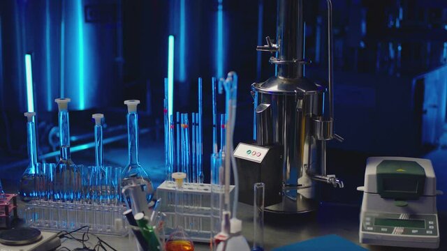 Medical or chemical development modern laboratory . Laboratory equipment , test tubes glasses on the table on background with blue lights . Dark room . Shot on ARRI ALEXA camera with dolly movement .