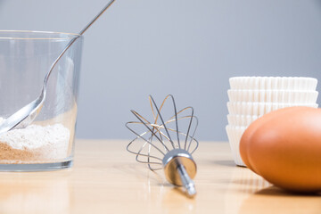 Closeup of raw eggs with a whisk and a glass of flour on the table