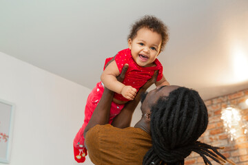 handsome african man with dreadlocks with little daughter at home 