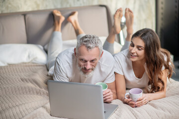 Man and woman with laptop on bed