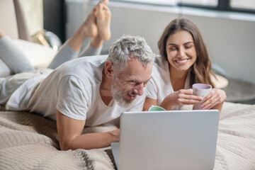 Husband and wife with coffee watching laptop
