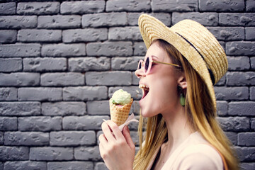 Pretty woman in elegant style hat outdoors ice cream brick wall on background