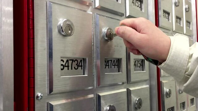 A woman finding the key to open pobox inside post office with 4k resolution