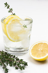 Refreshing lemon drink with ice and sprig of thyme