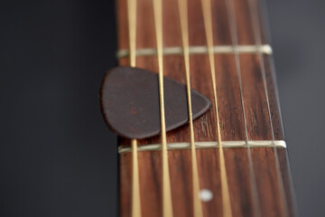 leisure, music and musical instruments concept - close up of bass guitar neck with pick between...