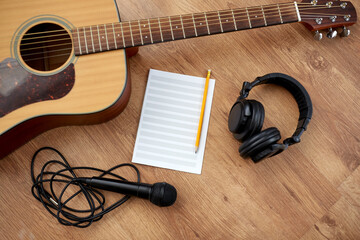 Fototapeta na wymiar composing and music writing concept - close up of acoustic guitar with music book, microphone and headphones on black table
