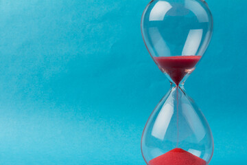 Crystal hourglass on blue background as a concept of passing time for business term, urgency and...