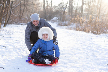 Father and kids riding on on ice sled, family have fun in winter nature
