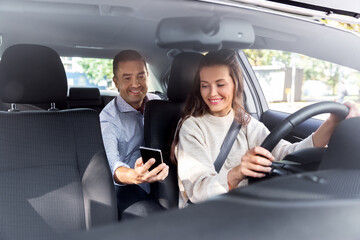 transportation, vehicle and people concept - male passenger showing smartphone to happy smiling female taxi car driver