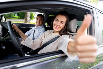 driver courses and people concept - car driving school instructor and young woman showing thumbs up to drive