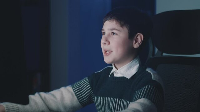 Happy Boy Reading Great News Online Using Computer While Sitting In Dark Room Late At Night At Home. Lucky Teen Schoolboy Celebrate Success Win Online Game And Showing YES Gesture.