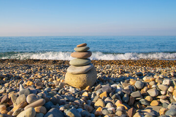 the concept of balance and harmony. stones on the beach in nature. A pyramid of stones on a beach of pebbles, in the background a blurred background of the sea and sky at dawn