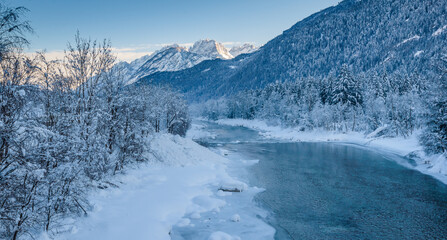 River, surrounded by snow-covered trees and a beautiful mountains in background.